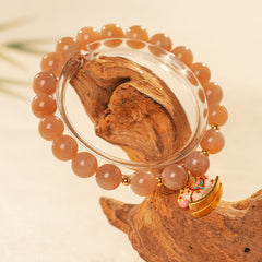 Peach sunstone beaded bracelet with a small gold-tone rocking horse charm — Sunstone Rocking Horse Bracelet by Glazenya.