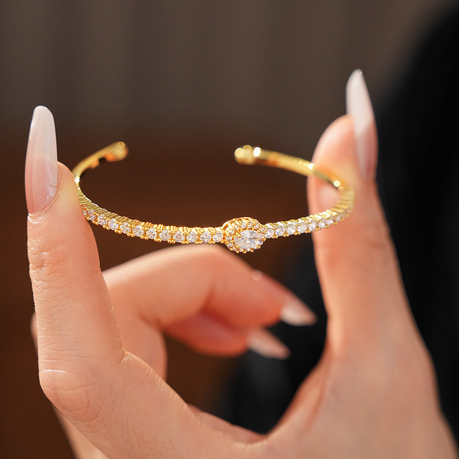 Elegant open bangle in gold with sparkling zircon stones and a marquise centerpiece, light-luxury adjustable bracelet.