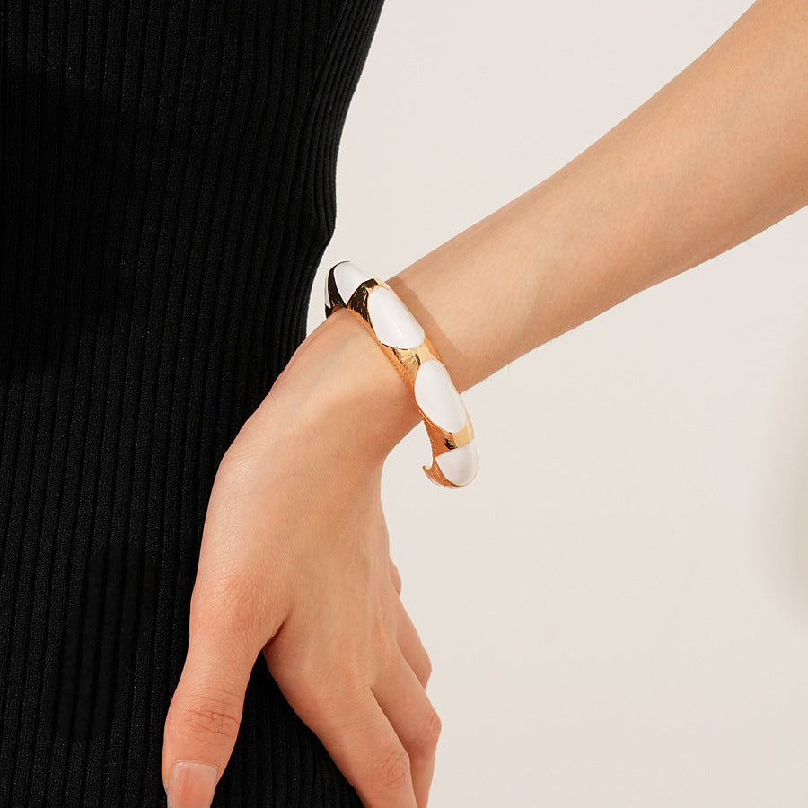 Gold-tone open cuff with triangular glossy enamel peaks; three variants (black, white, red) — Harlequin Enamel Cuff.