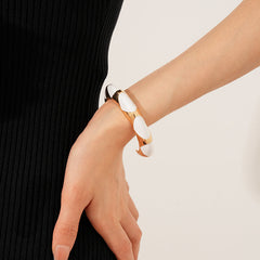 Gold-tone open cuff with triangular glossy enamel peaks; three variants (black, white, red) — Harlequin Enamel Cuff.