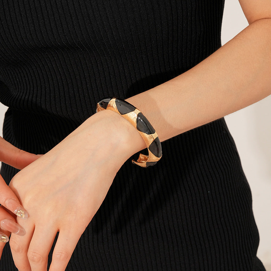 Gold-tone open cuff with triangular glossy enamel peaks; three variants (black, white, red) — Harlequin Enamel Cuff.