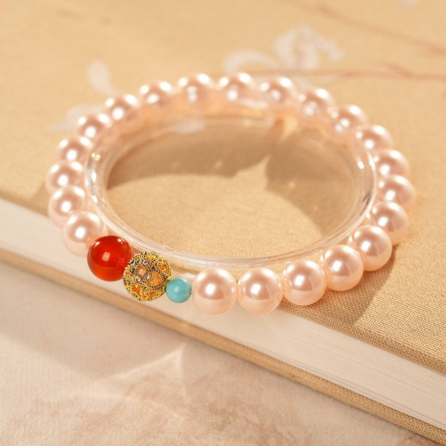 White/blush Shijia pearl bracelet featuring a red agate bead, gold zircon bead, and small blue accent — Trio Charm Pearl Bracelet by Glazenya.
