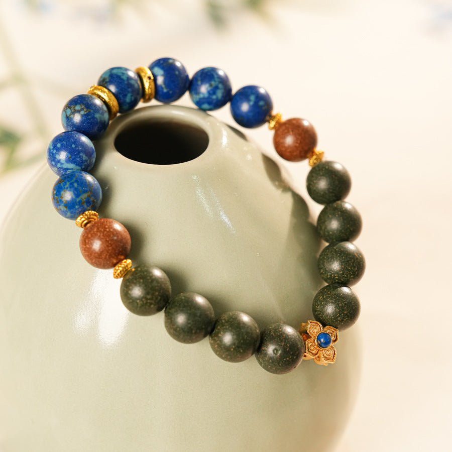 Wood-bead and lapis lazuli bracelet with a gold-tone floral charm set with a lapis cabochon — Woodland Lapis Charm Bracelet by Glazenya.