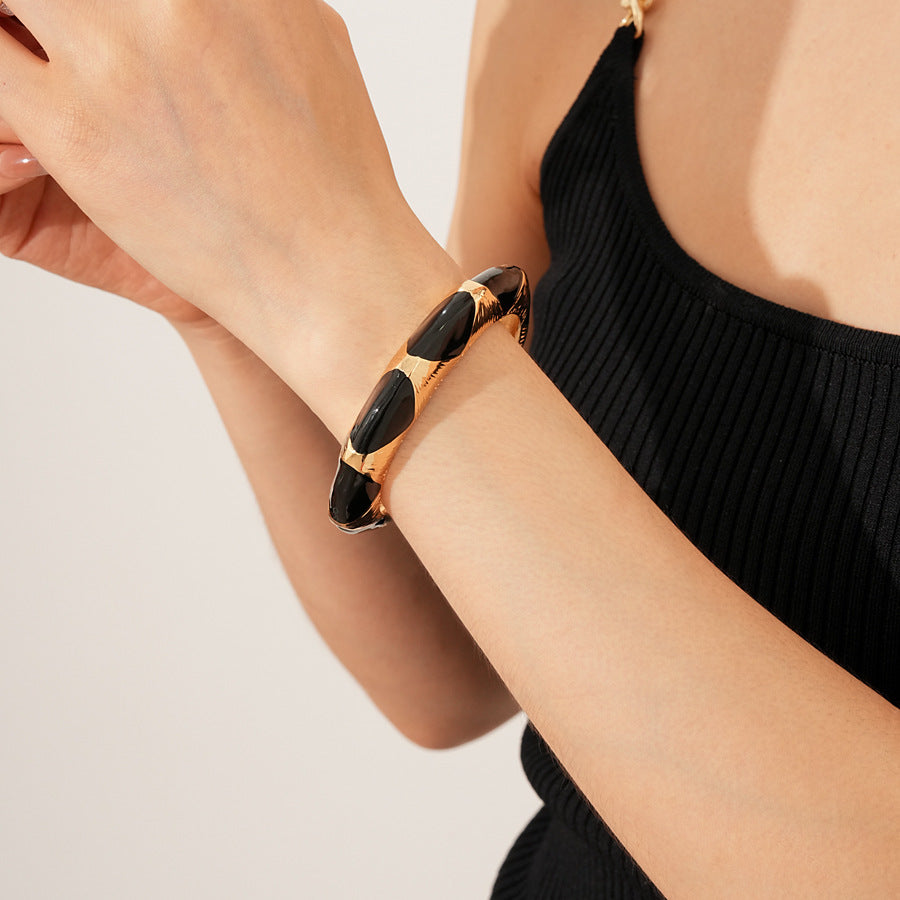 Gold-tone open cuff with triangular glossy enamel peaks; three variants (black, white, red) — Harlequin Enamel Cuff.