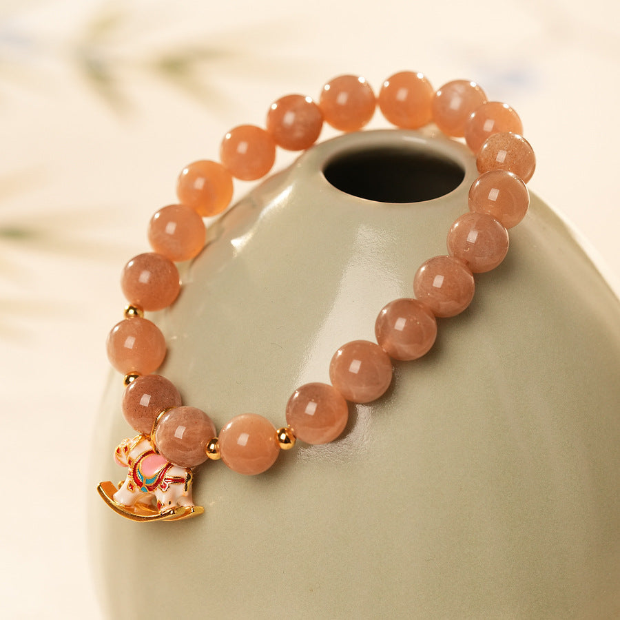 Peach sunstone beaded bracelet with a small gold-tone rocking horse charm — Sunstone Rocking Horse Bracelet by Glazenya.