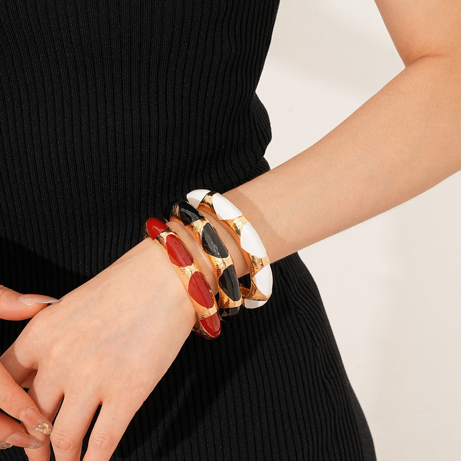 Gold-tone open cuff with triangular glossy enamel peaks; three variants (black, white, red) — Harlequin Enamel Cuff.