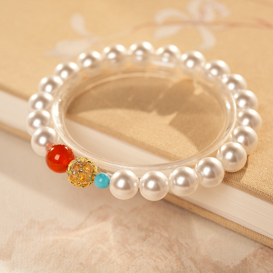 White/blush Shijia pearl bracelet featuring a red agate bead, gold zircon bead, and small blue accent — Trio Charm Pearl Bracelet by Glazenya.