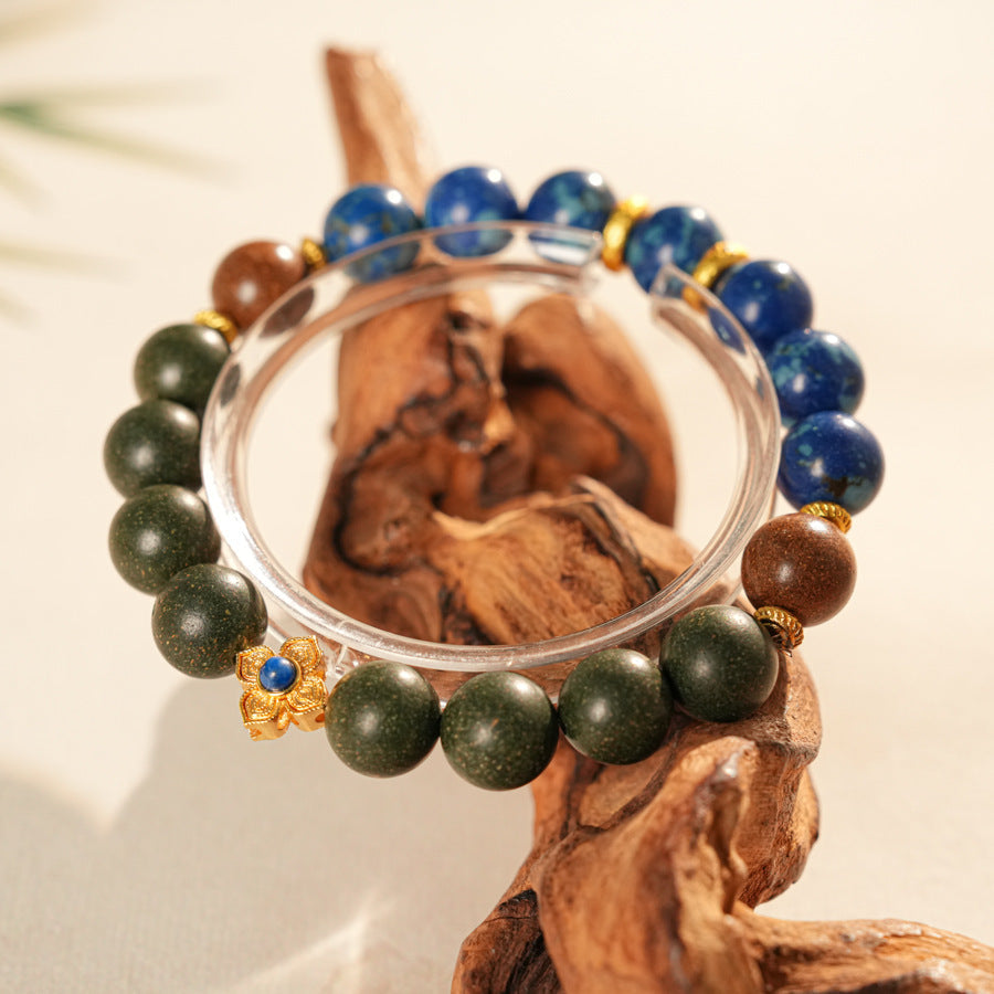 Wood-bead and lapis lazuli bracelet with a gold-tone floral charm set with a lapis cabochon — Woodland Lapis Charm Bracelet by Glazenya.