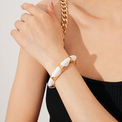 Gold-tone open cuff with triangular glossy enamel peaks; three variants (black, white, red) — Harlequin Enamel Cuff.