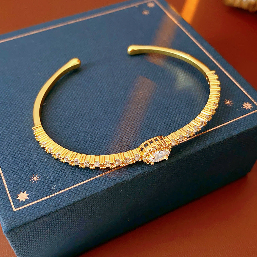 Elegant open bangle in gold with sparkling zircon stones and a marquise centerpiece, light-luxury adjustable bracelet.
