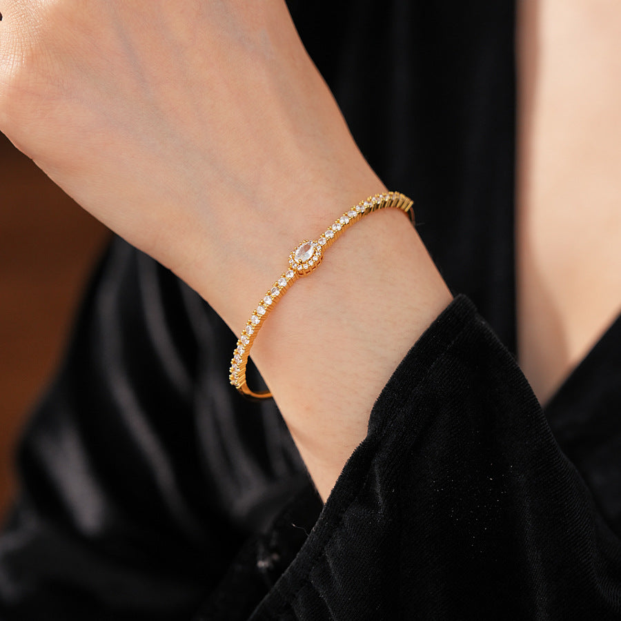 Elegant open bangle in gold with sparkling zircon stones and a marquise centerpiece, light-luxury adjustable bracelet.