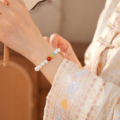 White/blush Shijia pearl bracelet featuring a red agate bead, gold zircon bead, and small blue accent — Trio Charm Pearl Bracelet by Glazenya.