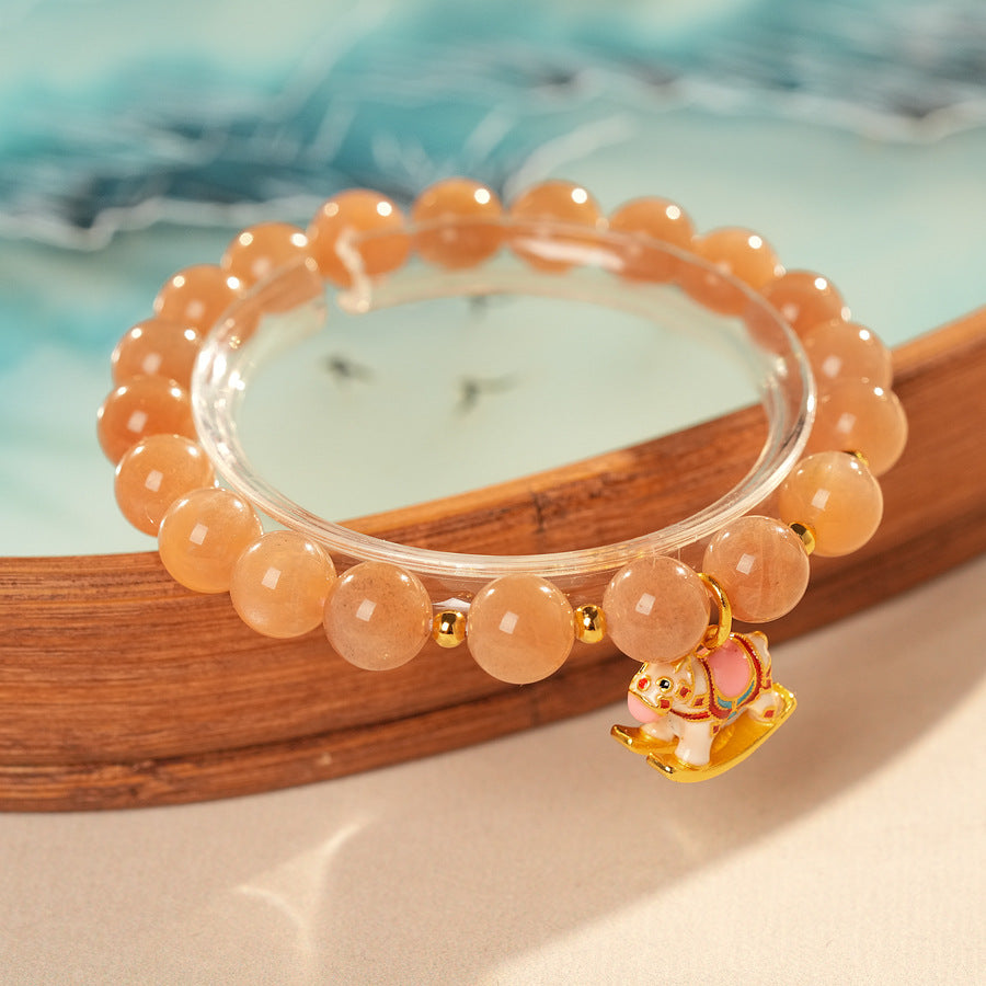 Peach sunstone beaded bracelet with a small gold-tone rocking horse charm — Sunstone Rocking Horse Bracelet by Glazenya.